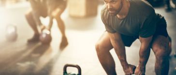 man lifting kettlebells