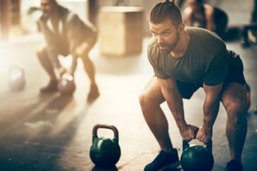 man lifting kettlebells
